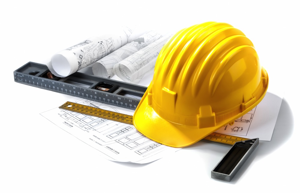 isolated hard hat with blueprints and rulers on white